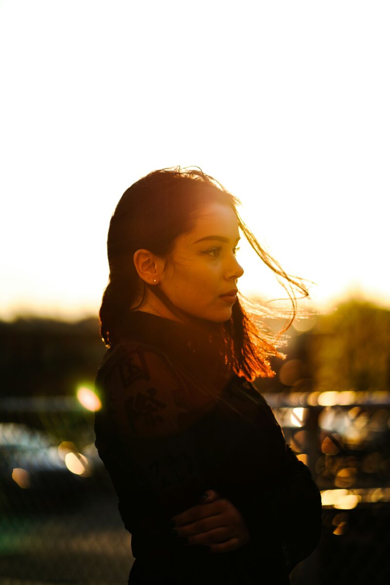Portrait d'une femme de profil éclairée par la lumière dorée d'un coucher de soleil.