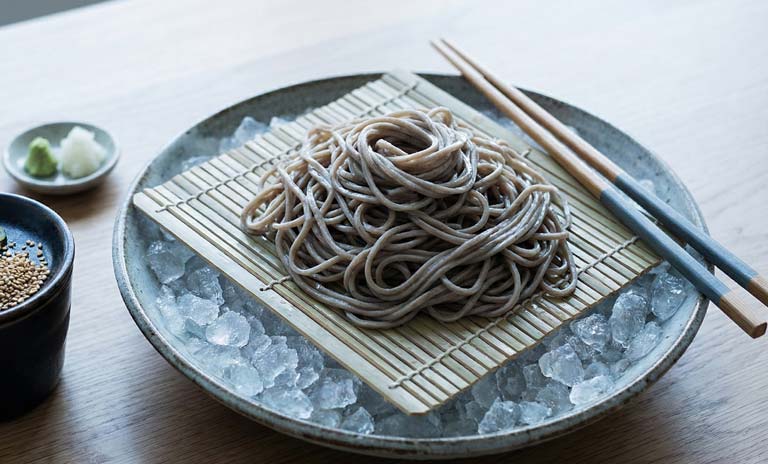 Nouilles brunes soba sur un lit de glace avec trempette soja à côté